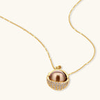 Elegant spherical pendant necklace and earrings set featuring crystal-pavé bottom half in gold or silver finish on white background.