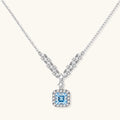 Sterling silver necklace with geometric crystal arrangement forming a V-shape and square blue moissanite centerpiece pendant