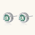 Round green moissanite stud earrings in sterling silver halo settings with brilliant sparkle on white background.