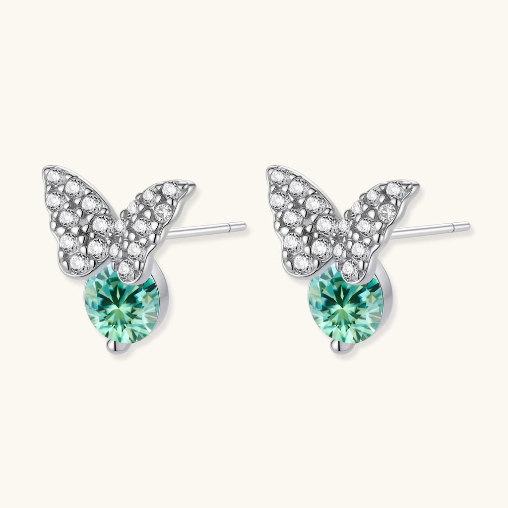 Sterling silver butterfly stud earrings with crystal wings and mint green center stones on cream background.