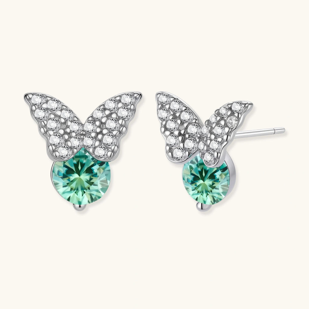 Sterling silver butterfly stud earrings with crystal wings and mint green center stones on cream background.