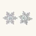 Sterling silver snowflake stud earrings with brilliant moissanite centers and intricate geometric patterns on cream background
